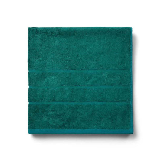 Et pænt foldet Bambooya Bambus badehåndklæde (70 x 140 cm) i Alpine Green med tre vandrette dekorative striber nær den ene kant, fremstillet af bambus, vist på en hvid baggrund.