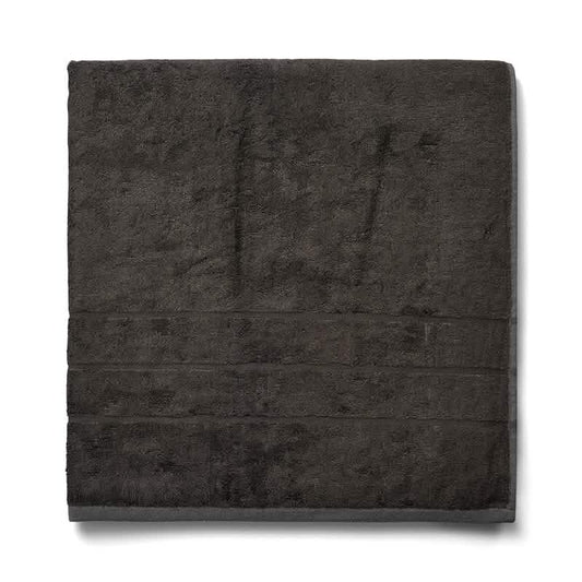 En pænt foldet Bambooya Bambus badelagen (90 x 180 cm) i Beluga, fremstillet af økologisk bomuld med en blød tekstur og subtile vandrette linjer nær kanten, OEKO-TECH Standard 100-certificeret, placeret på en hvid baggrund.