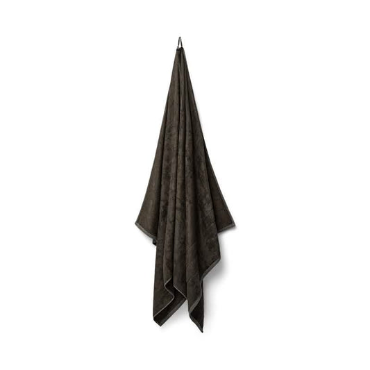 Et mørkegråt Bambooya Bambus badelagen (90 x 180 cm) hænger pænt på en krog mod en hvid baggrund. Det bløde, strukturerede håndklæde er OEKO-TECH Standard 100-certificeret.