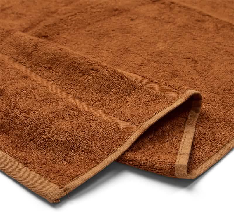 Et nærbillede af Bambooya Bambus badelagen (90 x 180 cm), vist foldet på en hvid baggrund. Håndklædet er fremstillet af blødt, struktureret økologisk bomuld og har et plysagtigt materiale og pænt afsluttede kanter.