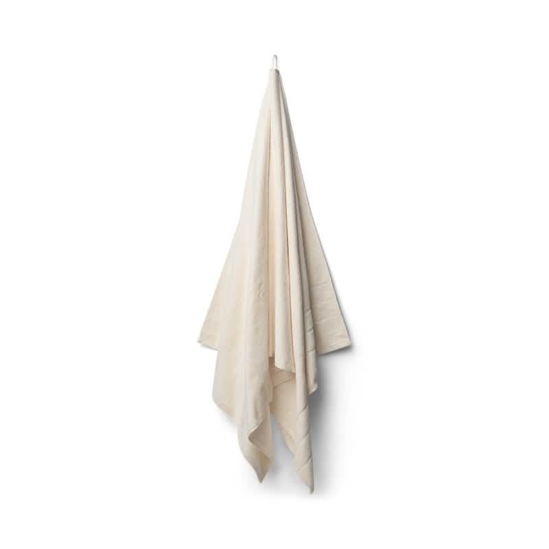Bambooya Bambus badelagen (90 x 180 cm) hænger på en enkelt krog mod en hvid baggrund og falder i bløde folder. Den er fremstillet af økologisk bomuld og er OEKO-TECH Standard 100-certificeret, så du kan føle dig tryg.