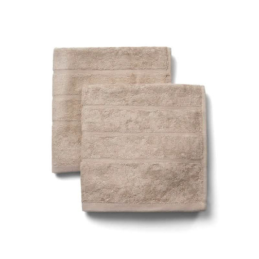 Et sæt med to Bambooya Bambus håndklæder (50 x 100 cm) i Bleached Sand med et diskret stribemønster, pænt foldet på en hvid baggrund.