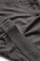 Nærbillede af mørkegrå stofshorts med en synlig forlomme og ordet bambooya præget på en matchende elastisk linning.